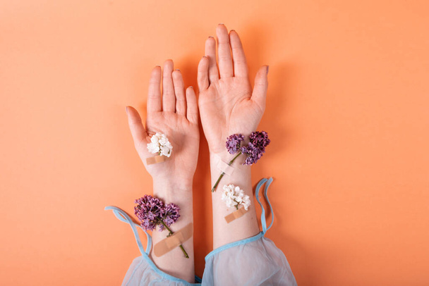 kädet tyttö lääketieteellinen kipsi lila kukkia oranssi tausta. käsite naisten terveys puhdas iho hygien - Valokuva, kuva
