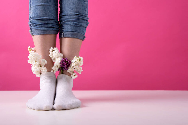 pernas de uma menina em meias que são inseridos um buquê de flores lilás em um fundo rosa. o conceito de saúde da mulher veias e perna - Foto, Imagem