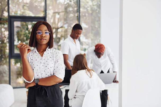 Beautiful woman in glasses in front of her colleagues. Group of african american business people working in office together. - Fotografie, Obrázek