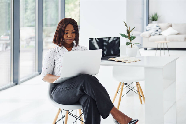 Jovem afro-americana em roupas formais está no escritório com laptop. - Foto, Imagem