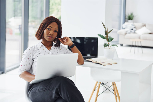 Resmi giyinmiş genç Afrikalı Amerikalı kadın ofiste dizüstü bilgisayarla bekliyor.. - Fotoğraf, Görsel