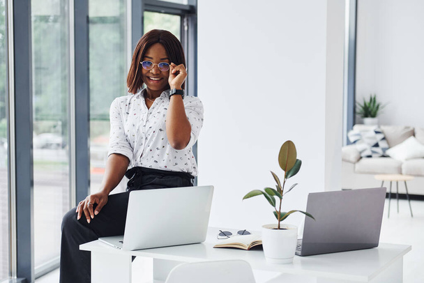 Giovane donna afroamericana in abiti formali è in ufficio con il computer portatile. - Foto, immagini