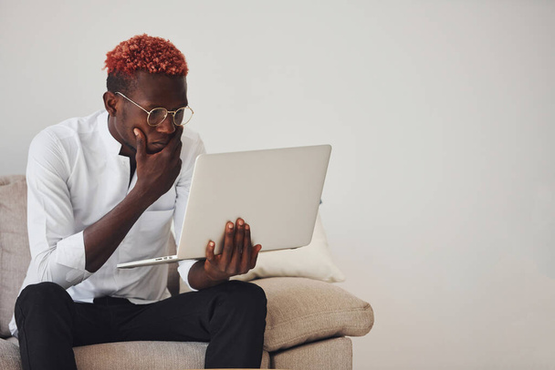 Young african american man in formal clothes indoors with laptop in hands. - Fotó, kép