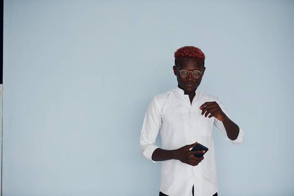 młody Afrykanin amerykański człowiek w biały formalne ubrania stojące pod ścianą w środku. - Zdjęcie, obraz