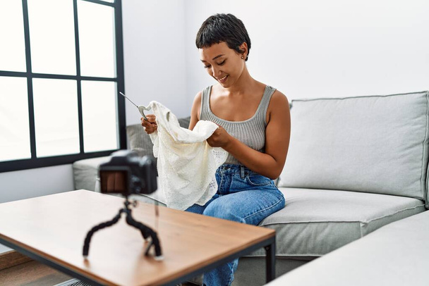 Young hispanic woman smiling confident sending clothes at home - Foto, imagen