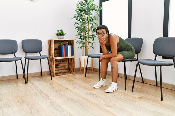 Young hispanic woman desperate sitting on chair at waiting room - Photo, Image