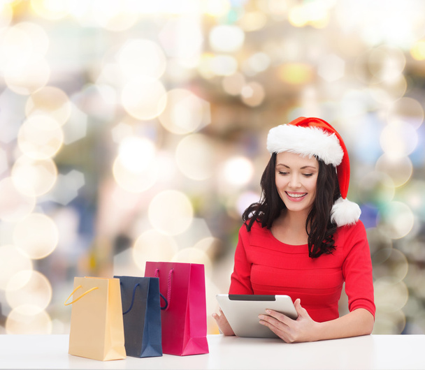 smiling woman in santa hat with bags and tablet pc - Φωτογραφία, εικόνα