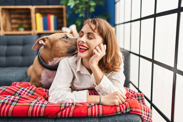 Young caucasian woman smiling confident lying on sofa with dog at home - Photo, Image