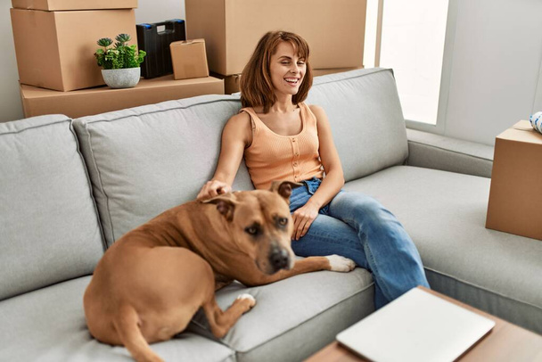 Nuori valkoihoinen nainen halaus koira istuu sohvalla kotona - Valokuva, kuva
