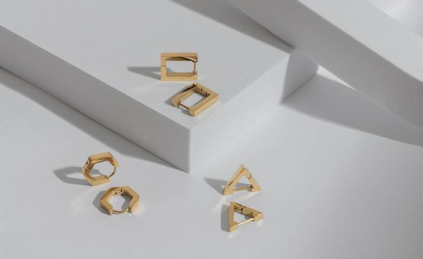 Bovenaanzicht van drie moderne geometrische vormen oorbellen paren op witte achtergrond met kopieerruimte - Foto, afbeelding