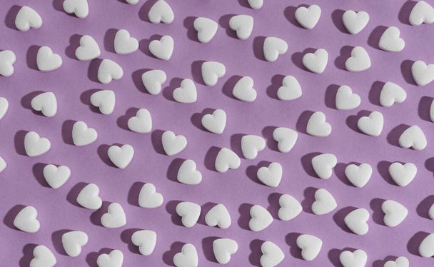 Вид сверху на безморщинистый рисунок белых сердечек на фиолетовом фоне - Фото, изображение