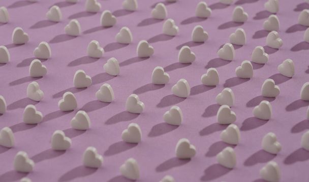 Zökkenőmentes minta szív alakú fehér tabletták lila háttér - fehér hall rózsaszín háttér - Fotó, kép