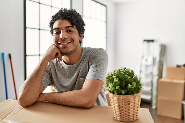 Young hispanic man smiling happy moving at new home. - 写真・画像