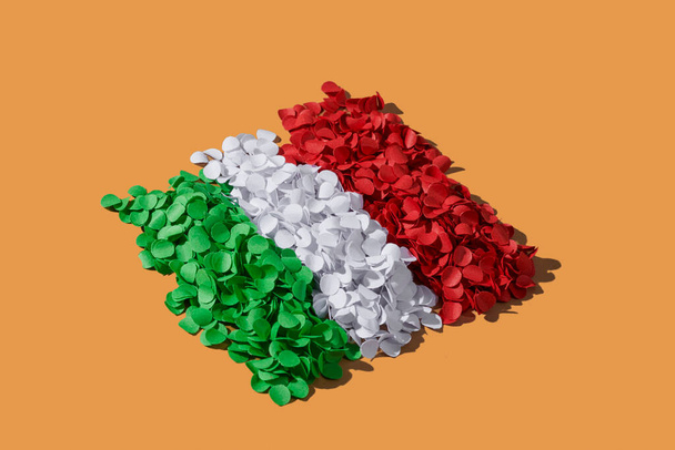 some stacks of green, white and red confetti arranged forming the national flag of Italy, on a brown background - Photo, Image