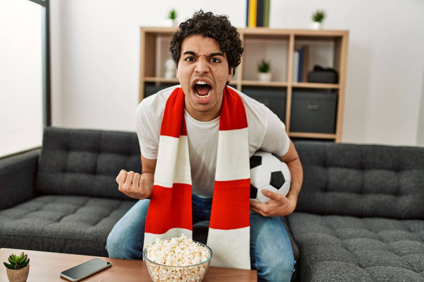 Junger hispanischer Mann beobachtet Fußballspiel und unterstützt Mannschaft zu Hause. - Foto, Bild