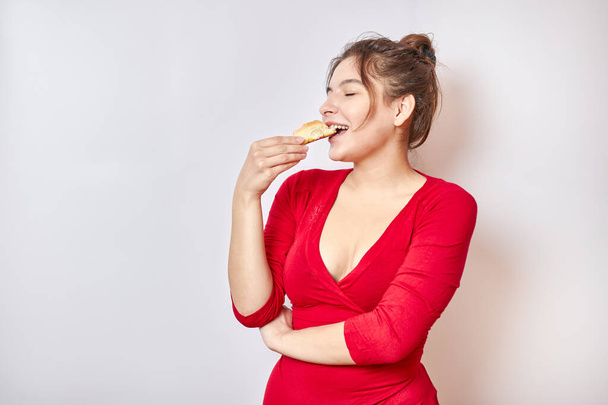 Beautiful girl in a red shirt enjoys a delicious cake. - 写真・画像