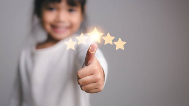 Cute little girl giving thumbs up with 5 stars approved - Photo, Image