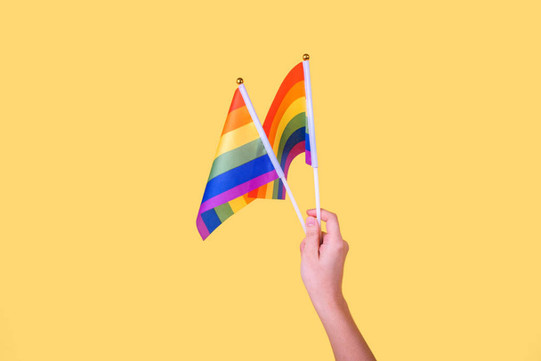 lgbt, relations homosexuelles et concept homosexuel - gros plan de la main d'un homme portant un bracelet de sensibilisation à la fierté gay tenant des drapeaux arc-en-ciel - Photo, image