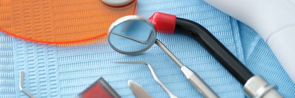 Instruments dentaires et prothèse dentaire reposent sur une serviette médicale bleue - Photo, image