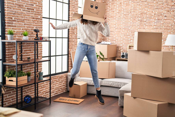 Genç bir kadın yeni evinde kafasında karton bir kutuyla dans ediyor. - Fotoğraf, Görsel