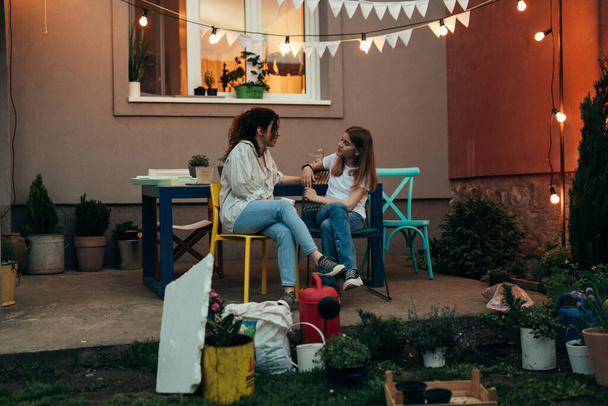teenage girl tells her mother about the events from school. they sit at a table in the yard - Fotoğraf, Görsel
