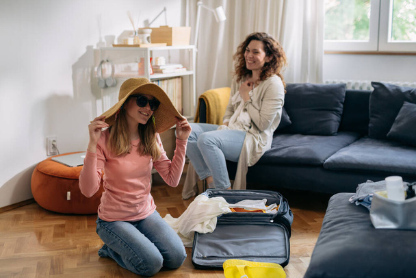 mother and daughter feels excited while packing bags for summer vacation - Фото, изображение