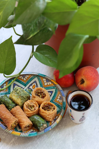 Baklava fecha a foto. Vida morta colorida com doces turcos tradicionais e xícara de chá preto em uma mesa. Deserto clássico do Oriente Médio.  - Foto, Imagem