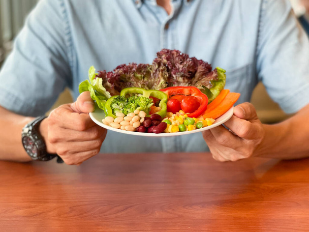 Die Hände des Mannes halten einen grünen Salat. Gesunder Lebensstil und vegetarisch-veganes Konzept, Intermittierendes Fasten. - Foto, Bild