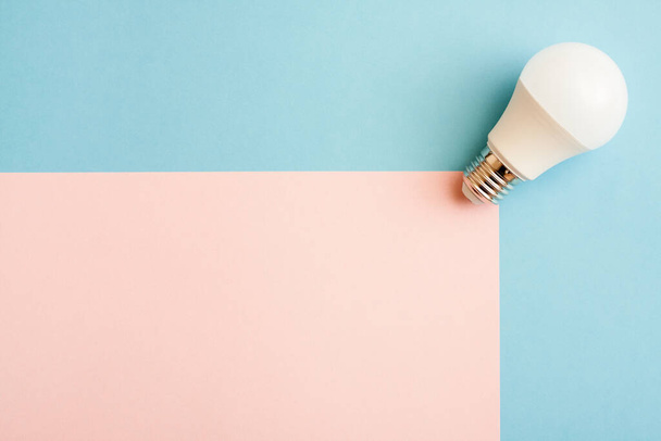 White light bulb on pink and blue background with free copy paste space. - Foto, Imagen