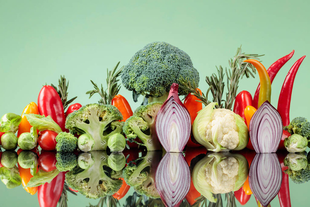 Composition of various raw vegetables on a green background. A conceptual image on the topic of vegetarianism. - Foto, immagini
