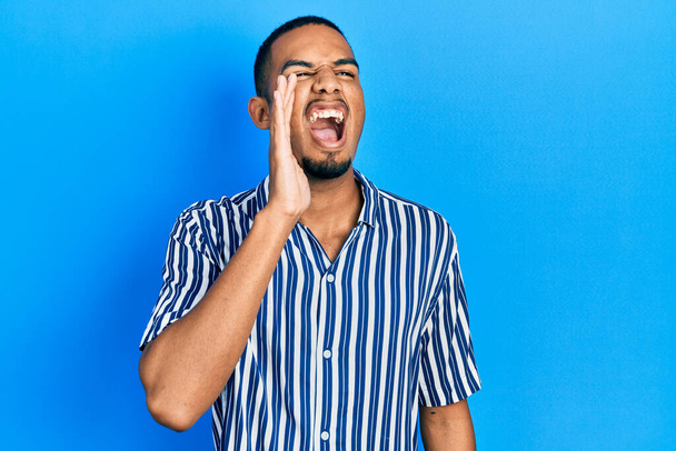 Young african american man wearing casual clothes shouting and screaming loud to side with hand on mouth. communication concept.  - Foto, imagen