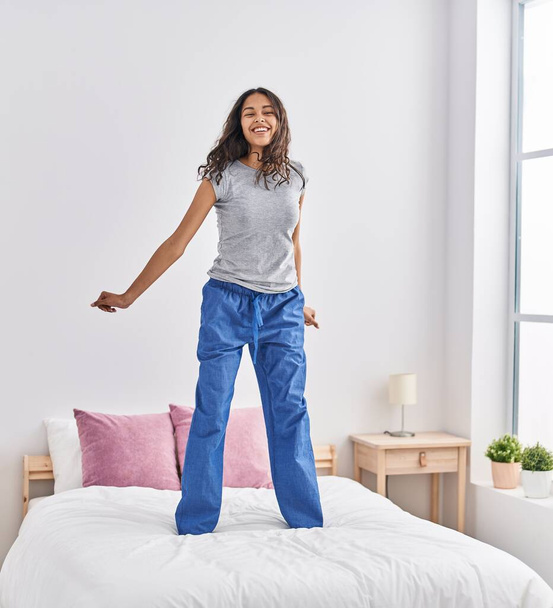 Fiatal afro-amerikai nő mosolyog magabiztos táncol az ágyon a hálószobában - Fotó, kép