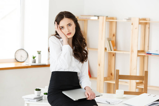 Zmęczona młoda bizneswoman cierpiąca na długi czas siedzi przy biurku komputera w biurze - Zdjęcie, obraz