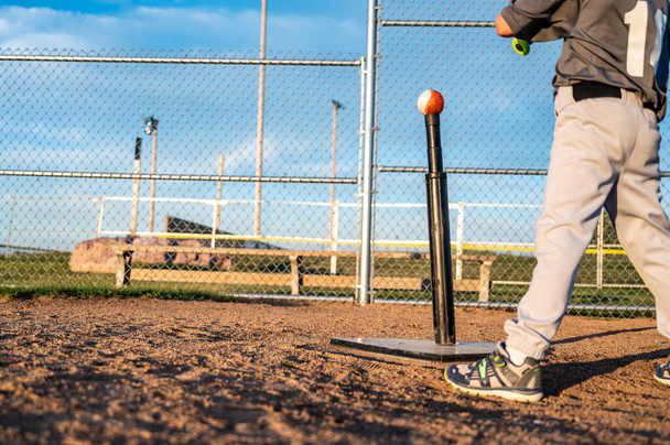 Youth baseball player standing at home plate to hit a ball off a tee with a bat. - Photo, image