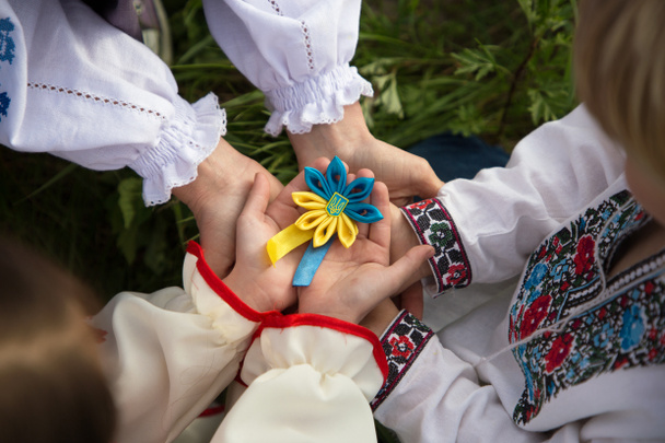 子供と大人の手に刺繍シャツを慎重に団結でウクライナの青黄色のシンボルトライデントを保持します。ウクライナに。愛国者国家の誇り。ウクライナで戦争を。助けを求める - 写真・画像