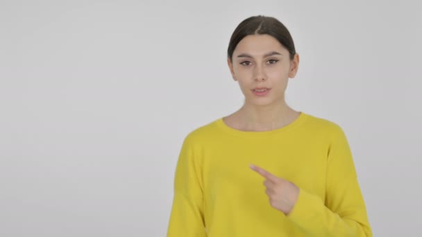 Ισπανίδα γυναίκα δείχνει προς το προϊόν σε λευκό φόντο - Πλάνα, βίντεο