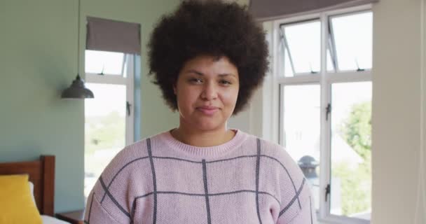Portrait of happy biracial woman smiling and looking at camera. spending quality time at home alone. - Materiał filmowy, wideo
