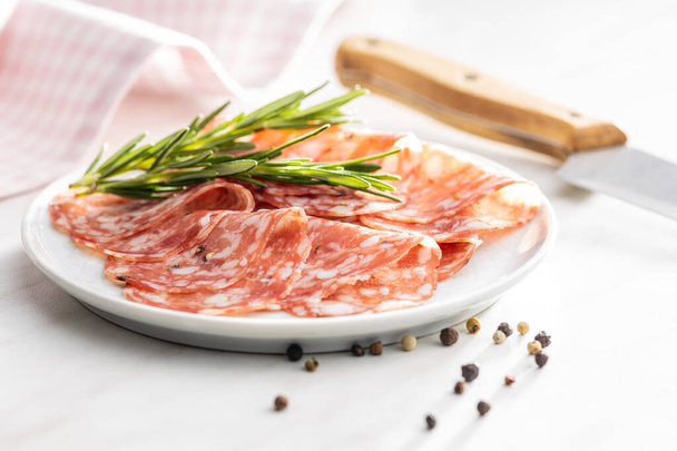 Sliced italian salami sausage with peppercorn on a plate. - Foto, afbeelding