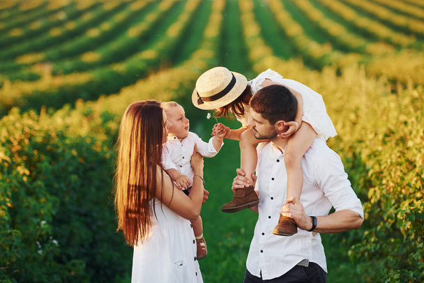 At agricultural field. Father, mother with daughter and son spending free time outdoors at sunny day time of summer. - Φωτογραφία, εικόνα