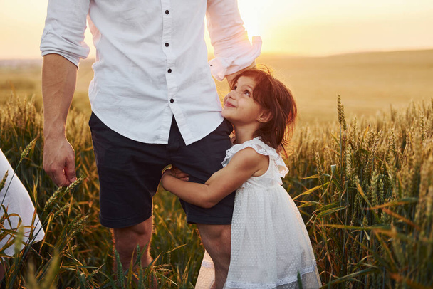 Girl embraces parent. Father with daughter spending free time on the field at sunny day time of summer. - Foto, Imagem