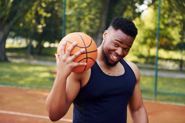 African american man standing with ball on the court outdoors. - Foto, afbeelding
