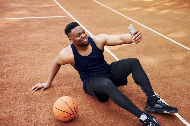 Making selfie. African american man plays basketball on the court outdoors. - Фото, зображення