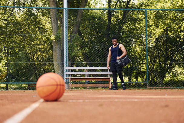 Beautiful green trees on background. African american man plays basketball on the court outdoors. - Fotoğraf, Görsel