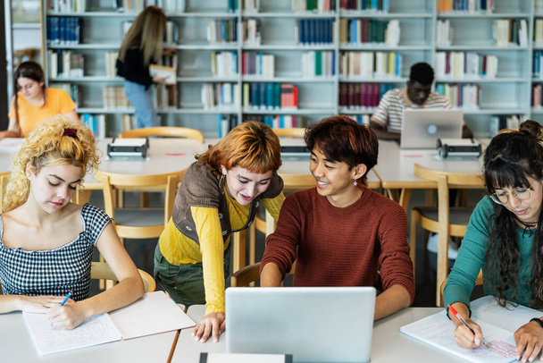 Jóvenes estudiantes universitarios usando laptop y estudiando con libros en la biblioteca - Concepto de educación escolar - Foto, Imagen