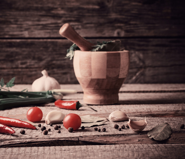 Mortar and pestle with pepper and spices on wooden table - Foto, Imagen