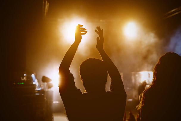Ευτυχισμένοι άνθρωποι που απολαμβάνουν ροκ συναυλία, σήκωσε τα χέρια και παλαμάκια της απόλαυσης, ενεργό έννοια νυχτερινή ζωή. - Φωτογραφία, εικόνα