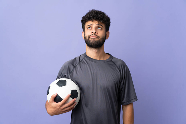 Багатий марокканський футболіст, ізольований на фіолетовому фоні, дивиться вгору. - Фото, зображення