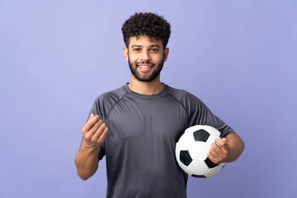 Handsome Moroccan young football player man over isolated on purple background making money gesture - Photo, Image