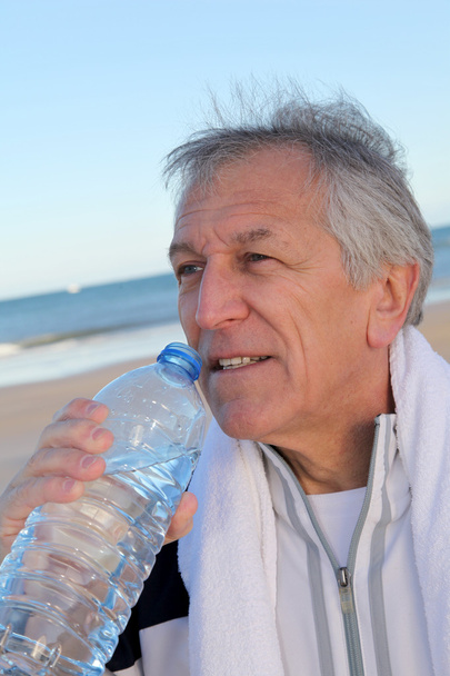 :Active senior drinking water from bottle at the beach - Zdjęcie, obraz