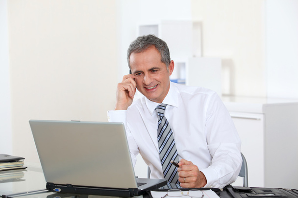 Portrait of smiling businessman in front of computer - Foto, afbeelding